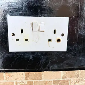 Burnt electrical socket showing heat damage discovered during an EICR inspection in a London property.