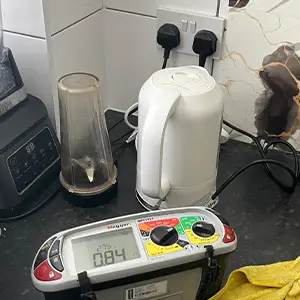 Megger tester displaying a Zs reading of 0.84 ohms on a kitchen ring final circuit during an EICR.
